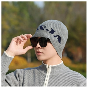 Detail of grey knitted beanie with blue letter pattern and matching zip-up sweater