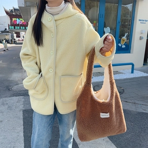 Detail of soft yellow sherpa hooded jacket with large pockets and brown plush tote bag