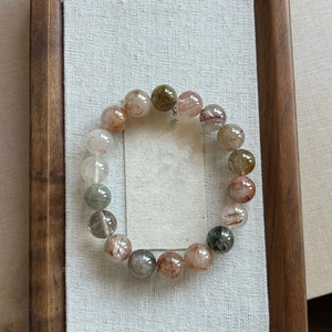 Detailed view of natural multi-color rutilated quartz beads on a soft linen background