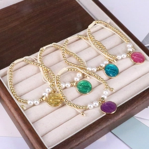 Detail of bohemian woven bracelets with colorful oil-drop charms and pearls in a box