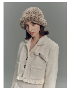 Detail of a brown faux fur bucket hat and white plush jacket with silver square buttons
