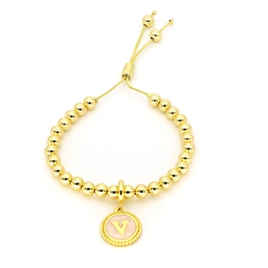 Détail macro du bracelet en perles dorées 18k avec pendentif lettre V en émail rose