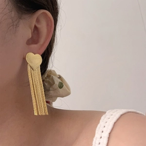 Macro detail of long gold heart fringe earrings on model showcasing elegant tassel length