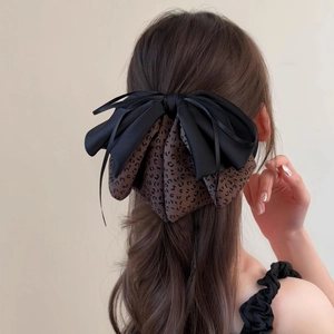 Detail of layered bow hair claw featuring black satin and brown leopard print textures