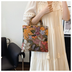 Close-up of brown floral embroidery with sequins and bamboo handles on vintage linen handbag