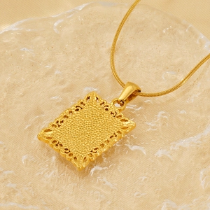 Detail view of a gold square pendant with filigree edges and textured surface on a gold chain