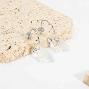 Detailed view of silver stainless steel earrings with faceted clear geometric pendants