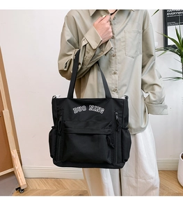 Detail view of large capacity black tote bag with white lettering and multiple pockets