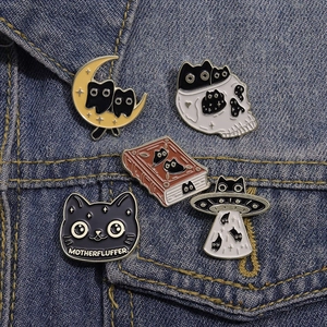 Set of 5 cartoon cat enamel pins on denim jacket featuring moon and book motifs