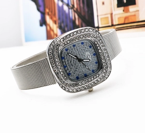 Macro detail of square silver watch featuring rhinestone bezel and blue crystal hour markers
