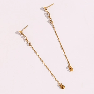 Detail of long gold tassel earrings with square cubic zirconia on a white background