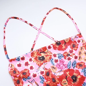 Detail of slim pink floral dress featuring thin cross straps and smooth satin fabric