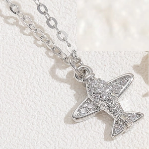 Macro shot of silver airplane pendant necklace with sparkling cubic zirconia pavé details