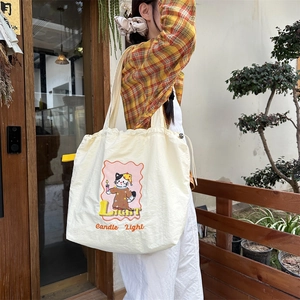 Detail of embroidered cat pattern on beige canvas tote bag with drawstring closure