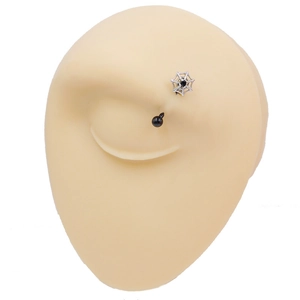 Close-up of curved eyebrow ring with silver spider web design and black gemstone inlay