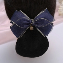 Detail of navy blue denim hair bow with gold trim and pendant on a bun hairstyle