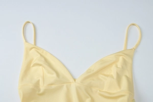 Detail view of light yellow V-neck camisole top with thin straps and soft elastic fabric