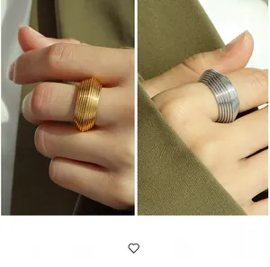 Detailed close-up of chunky gold and silver multi-layered ribbed band rings on hand