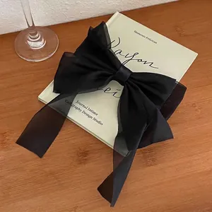 Detail of a black organza bow hair clip elegantly placed on an artistic book page