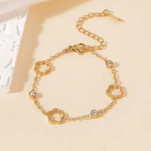 Detail of gold titanium steel bracelet with hollow flower charms and zircon stones