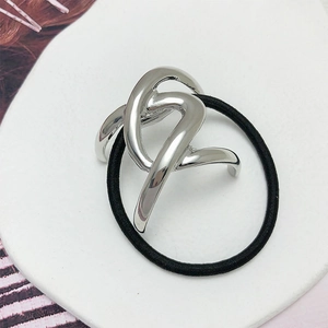 Close-up of a silver irregular metal hair ring with a polished mirror finish on white tray