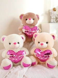 Detailed view of plush teddy bears in brown and white holding shiny pink LOVE hearts