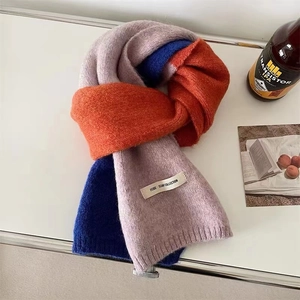 Détail d'une écharpe en maille douce à blocs de couleurs rose, orange, bleu et étiquette