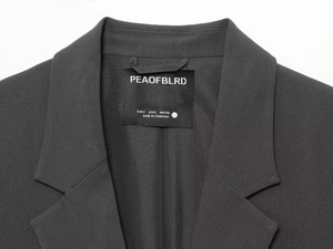 Detailed close-up of dark grey suit collar and inner label showing size S