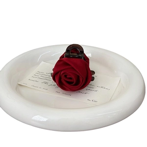 Elegant deep red silk rose flower hair claw clip on a white ceramic plate for women