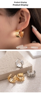 Close-up of geometric C-shaped hoop earrings with gold and silver striped textures