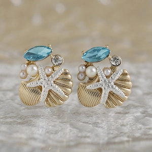 Dettaglio di orecchini con stelle marine, pietre azzurre e piccole perle bianche