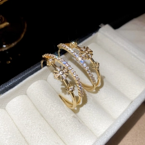 Vue détaillée des boucles d'oreilles double C plaquées or 18 carats avec fleurs en zircon
