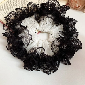 Détail d'un chouchou à pois avec dentelle noire superposée dans un style vintage français