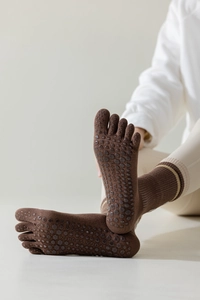Detailed view of brown five-toe yoga socks with non-slip grip particles on soles