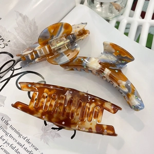 Detail of amber acetate hair claws with colorful rhinestones on a magazine background