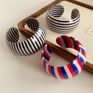 Close-up of resin open bangles with geometric stripes in pop art style on a tray