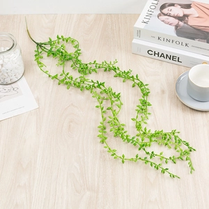 Realistic green artificial succulent vines displayed on a wooden table with lifestyle decor