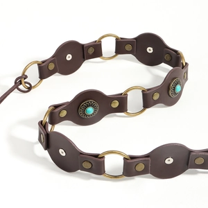 Detail of dark brown leather belt with turquoise stones and brass metal rings on white base