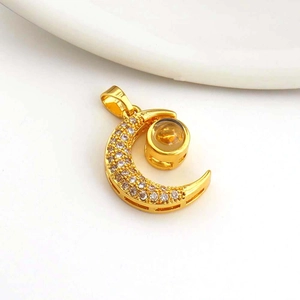 Macro shot of gold-plated moon pendant with white zircon stones and projection lens