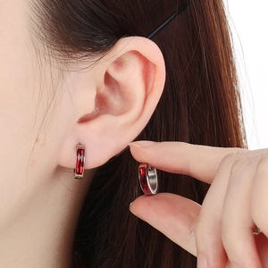 Detail of silver hoop earring with rectangular red gemstone worn on the ear for size reference