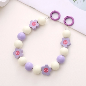 Detail of purple and white flower beaded strap with circular spring clasps on desk