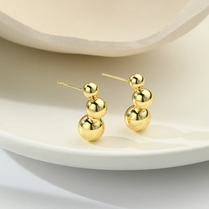 Detail of three-ball minimalist 18k gold earrings showing S925 hallmark on the post