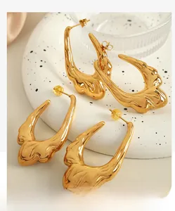 Detailed macro view of irregular molten texture gold earrings on a marble tray