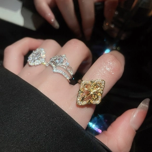 Detailed close-up of stacked rings featuring silver flower zircon and gold hollow square design