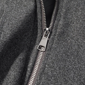 Detailed close-up of a silver metal zipper on a dark grey wool coat fabric