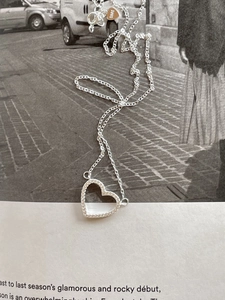 Macro detail of a 925 sterling silver heart pendant with zircon on a magazine page