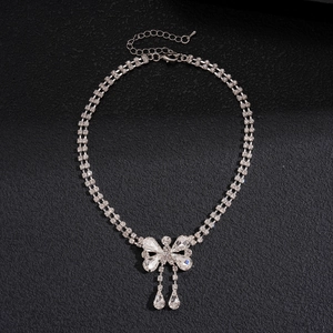 Detailed macro view of silver bow pendant with crystal teardrop tassels on double chain