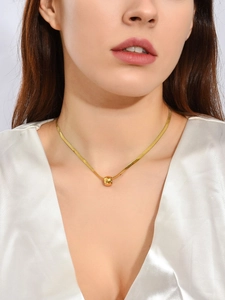 Detalle de un collar de cadena de serpiente dorada con colgante de perla geométrica