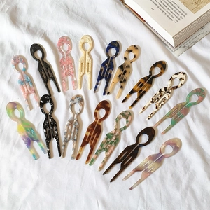 Set of 14 acetate U-shaped hair pins with tortoiseshell and marble patterns on white fabric