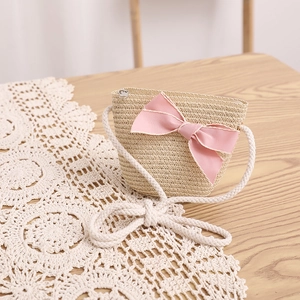 Détail du sac bandoulière en paille avec grand nœud en satin rose et bandoulière